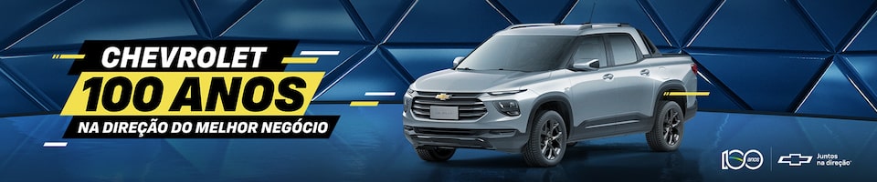 Imagem de uma picape Chevrolet cinza em uma superfície refletiva com um fundo azul geométrico. O texto à esquerda diz Chevrolet 100 Anos, Na Direção do Melhor Negócio. Os logotipos e a marca Chevrolet estão no canto inferior direito.