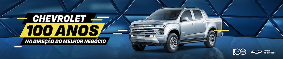 Imagem de uma picape Chevrolet cinza em uma superfície refletiva com um fundo azul geométrico. O texto à esquerda diz Chevrolet 100 Anos, Na Direção do Melhor Negócio. Os logotipos e a marca Chevrolet estão no canto inferior direito.