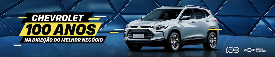 Um Chevrolet SUV prateado é exibido contra um fundo geométrico azul. O texto diz: Chevrolet 100 anos na direção do melhor negócio. Os logotipos incluem 100 anos e o símbolo da Chevrolet com a frase Juntos na mesma direção.