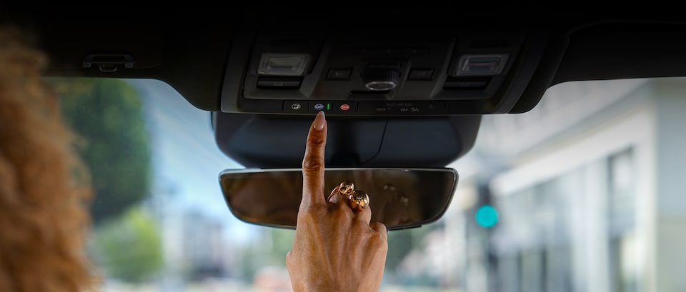 Uma mão selecionando o OnStar no teto de um veículo Chevrolet 