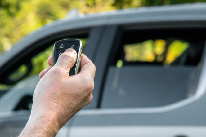 Imagem de uma mão acionando o controle remoto para a subida dos vidros da nova picape Chevrolet Silverado, ao fundo da foto.