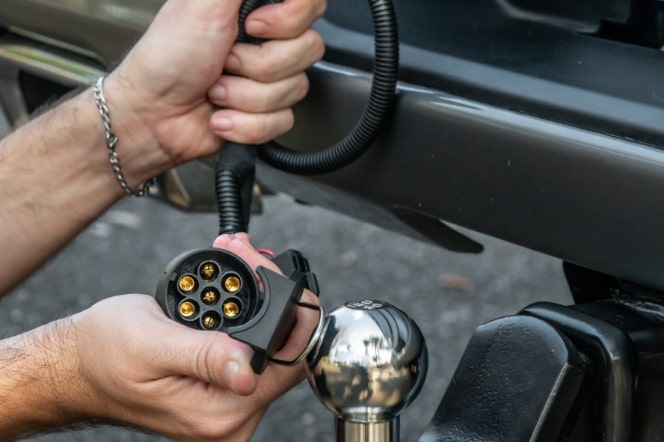 Imagem mostrando as mão de um homem instalando o acessório engate, na traseira da nova picape Chevrolet Silverado.