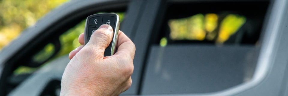 Imagem de uma mão acionando o controle remoto para a subida dos vidros da nova picape Chevrolet Silverado, ao fundo da foto.