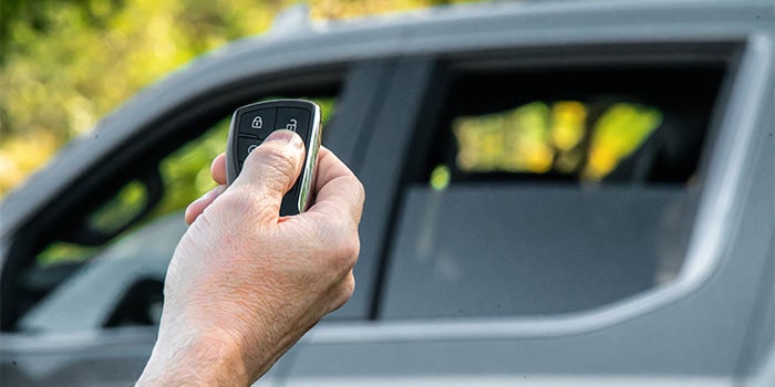 Imagem de uma mão acionando o controle remoto para a subida dos vidros da nova picape Chevrolet Silverado, ao fundo da foto.