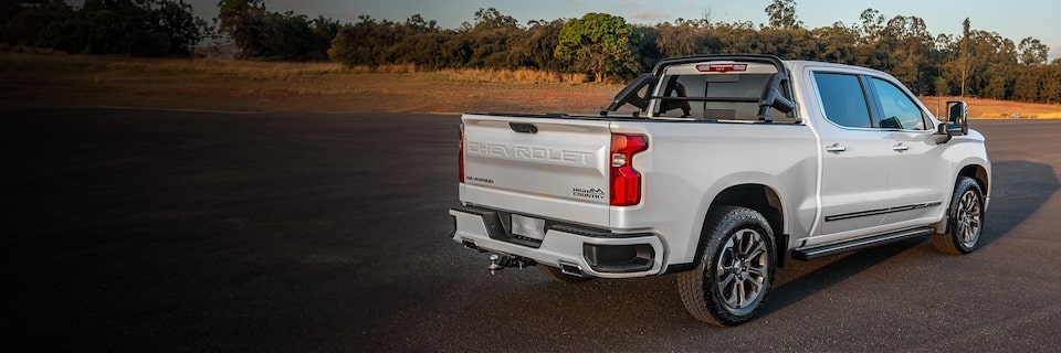 Imagem da nova picape Chevrolet Silverado, branco summit, andando em uma estrada rural.