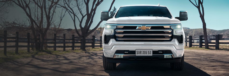 Nova picape Chevrolet Silverado, branco summit, em estrada de terra de uma fazenda.